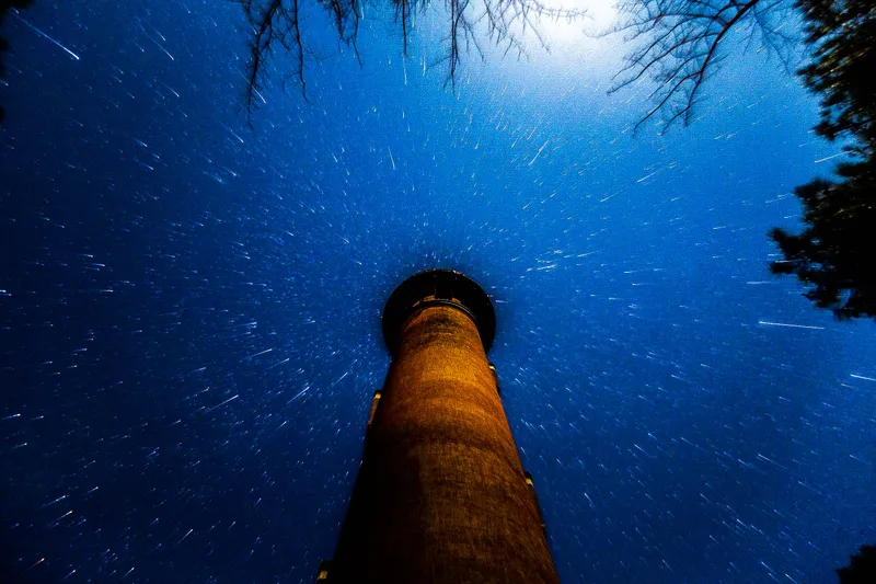 Currituck Beach Lighthouse illuminated at night with star trails in the winter sky above Corolla