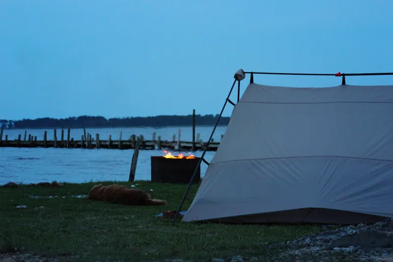 Camping site along Currituck Sound at sunset, with tent set up on a grassy area overlooking the calm water