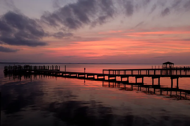 Vivid sunset colors over Currituck Sound viewed from the Duck boardwalk with dramatic cloud reflections on the water