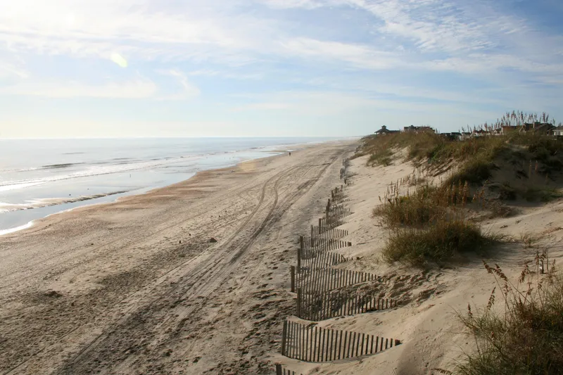 Wide empty beach on the northern Outer Banks near Corolla at sunrise, with soft morning light and calm surf stretching into the distance