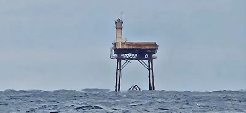 Diamond Shoals Light Tower standing in the Atlantic Ocean off Cape Hatteras, the distinctive red-and-white platform marking the dangerous shoals near Hatteras Village