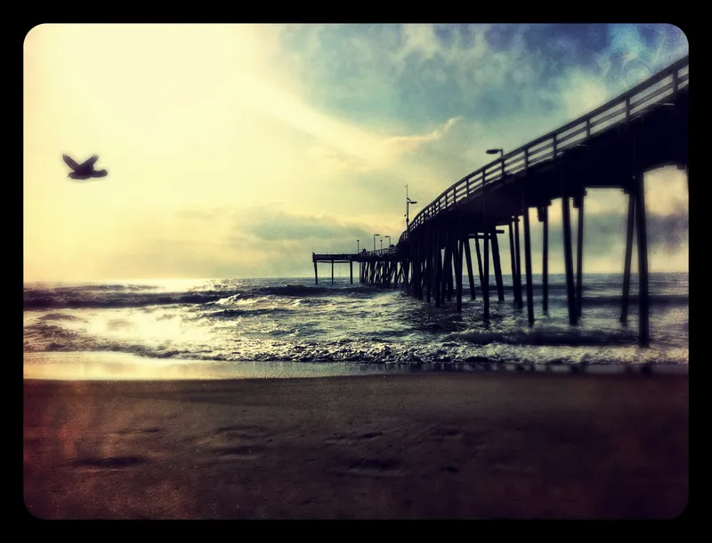 Avon fishing pier extending into the Atlantic Ocean with beach and waves in the foreground, Hatteras Island