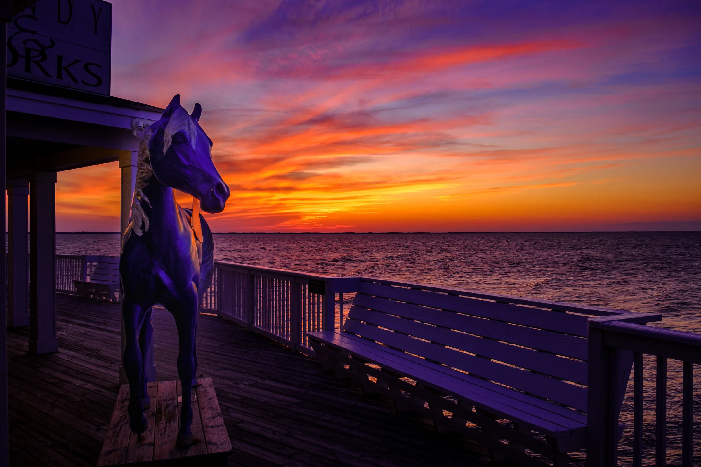 Golden sunset over the Duck boardwalk with warm light reflecting on the wooden planks and Currituck Sound in the background