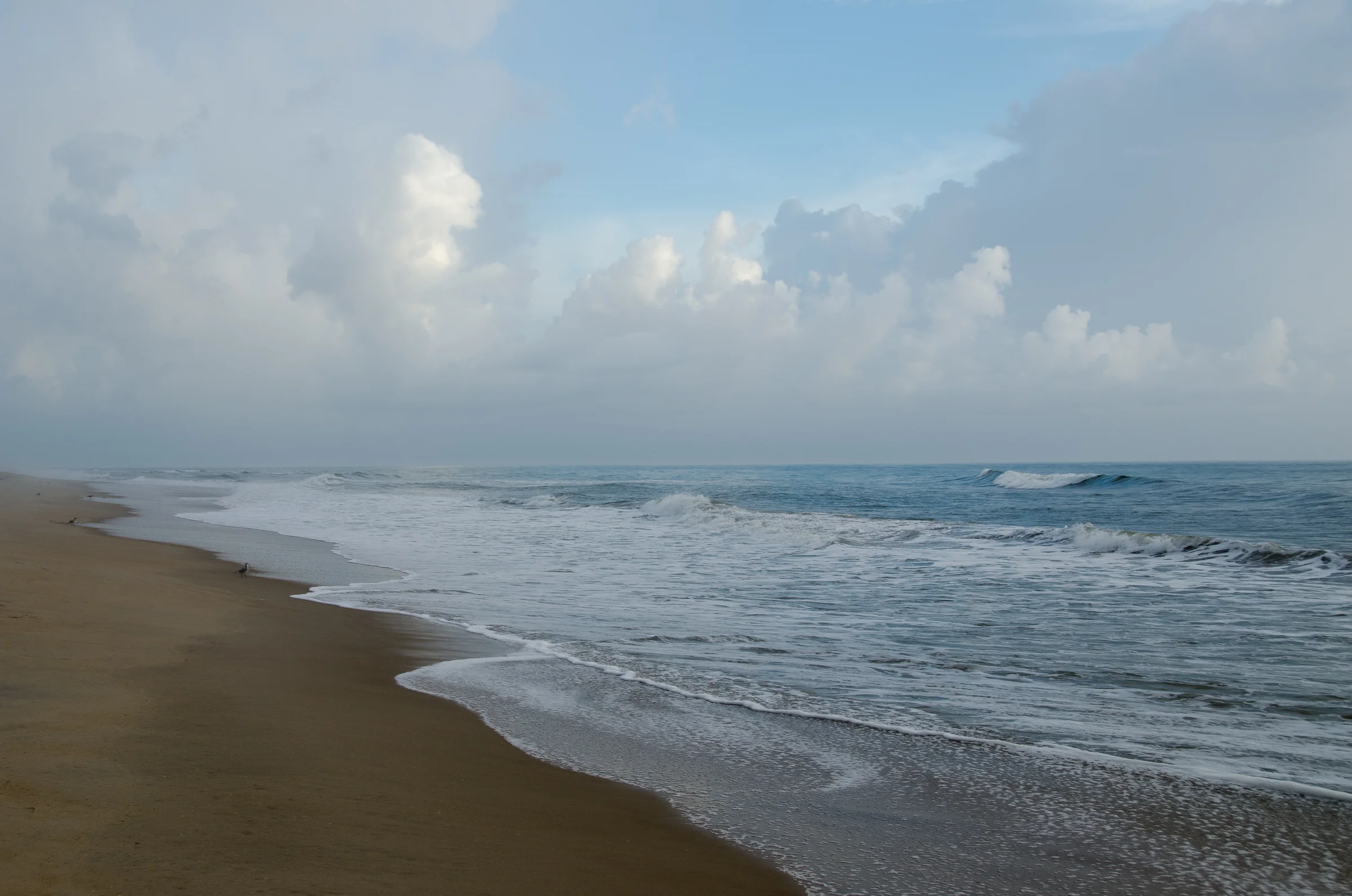 Vibrant sunrise over the beach at Kill Devil Hills with golden and pink clouds reflected on wet sand