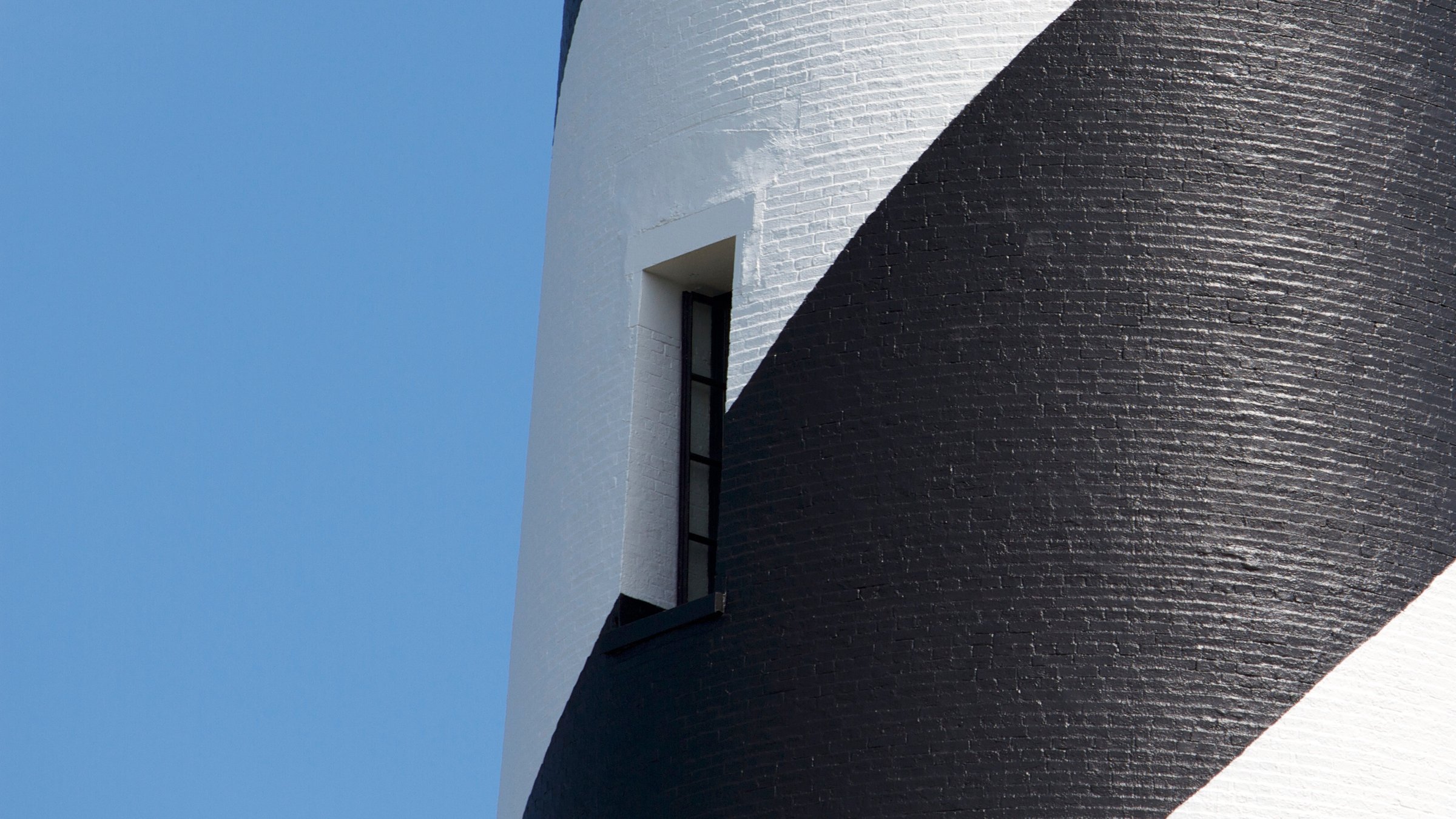 Cape Hatteras Lighthouse with its distinctive black and white spiral pattern rising above the beach and maritime forest at Buxton
